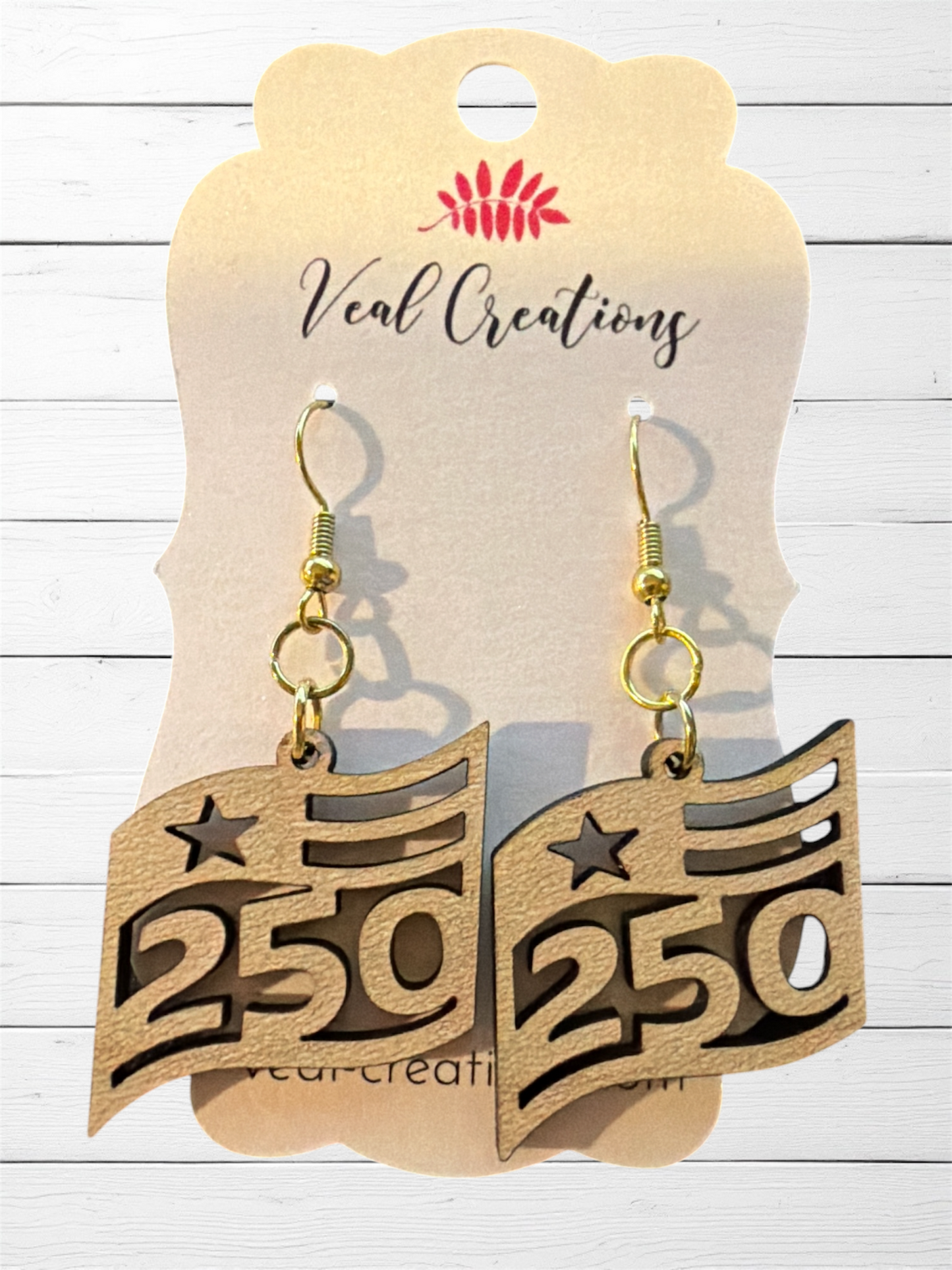 Wooden earrings with '250' design on a 'Veal Creations' branded card.