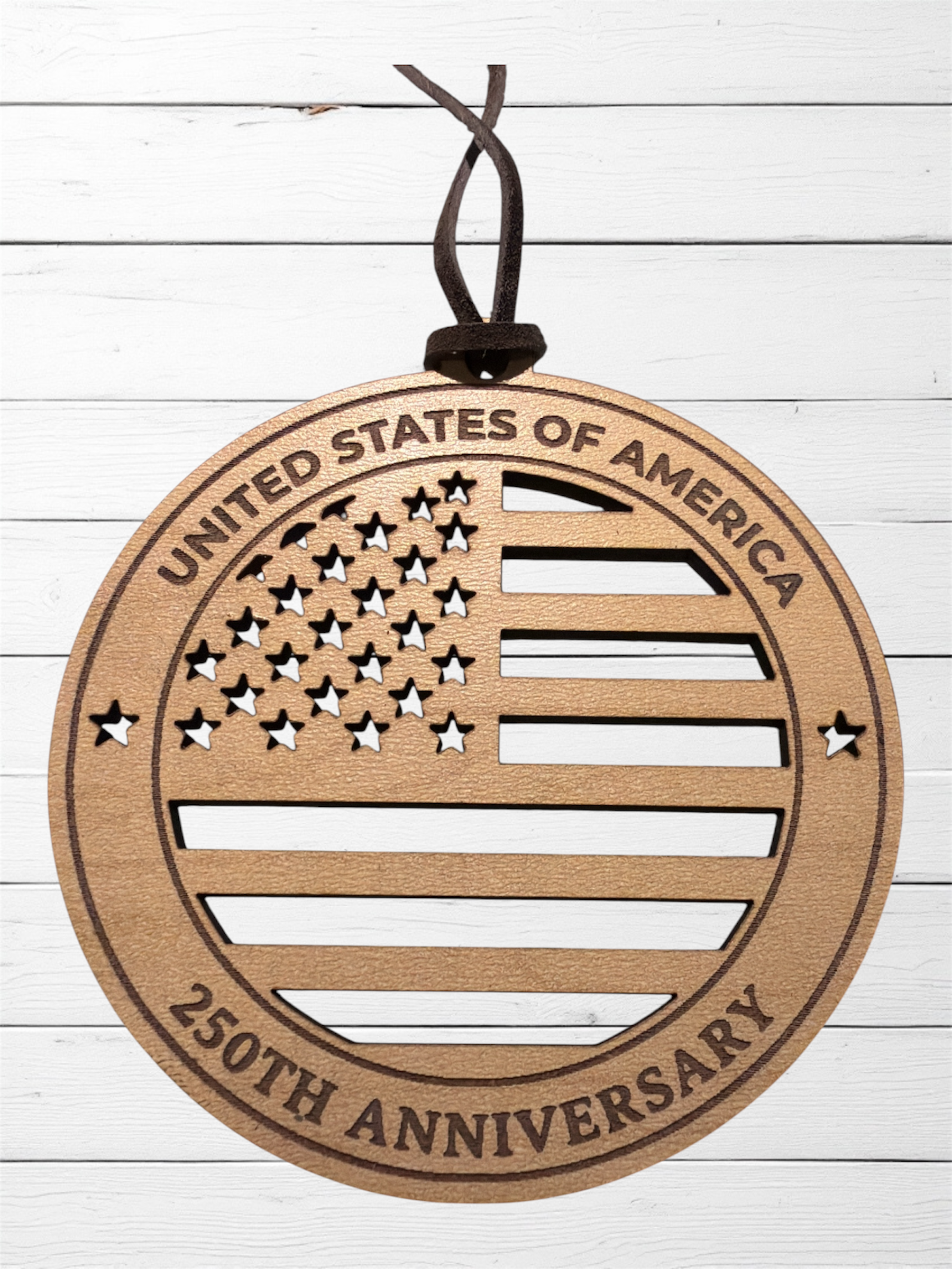 Wooden ornament with American flag design and 'United States of America 250th Anniversary' text on a white wooden background.