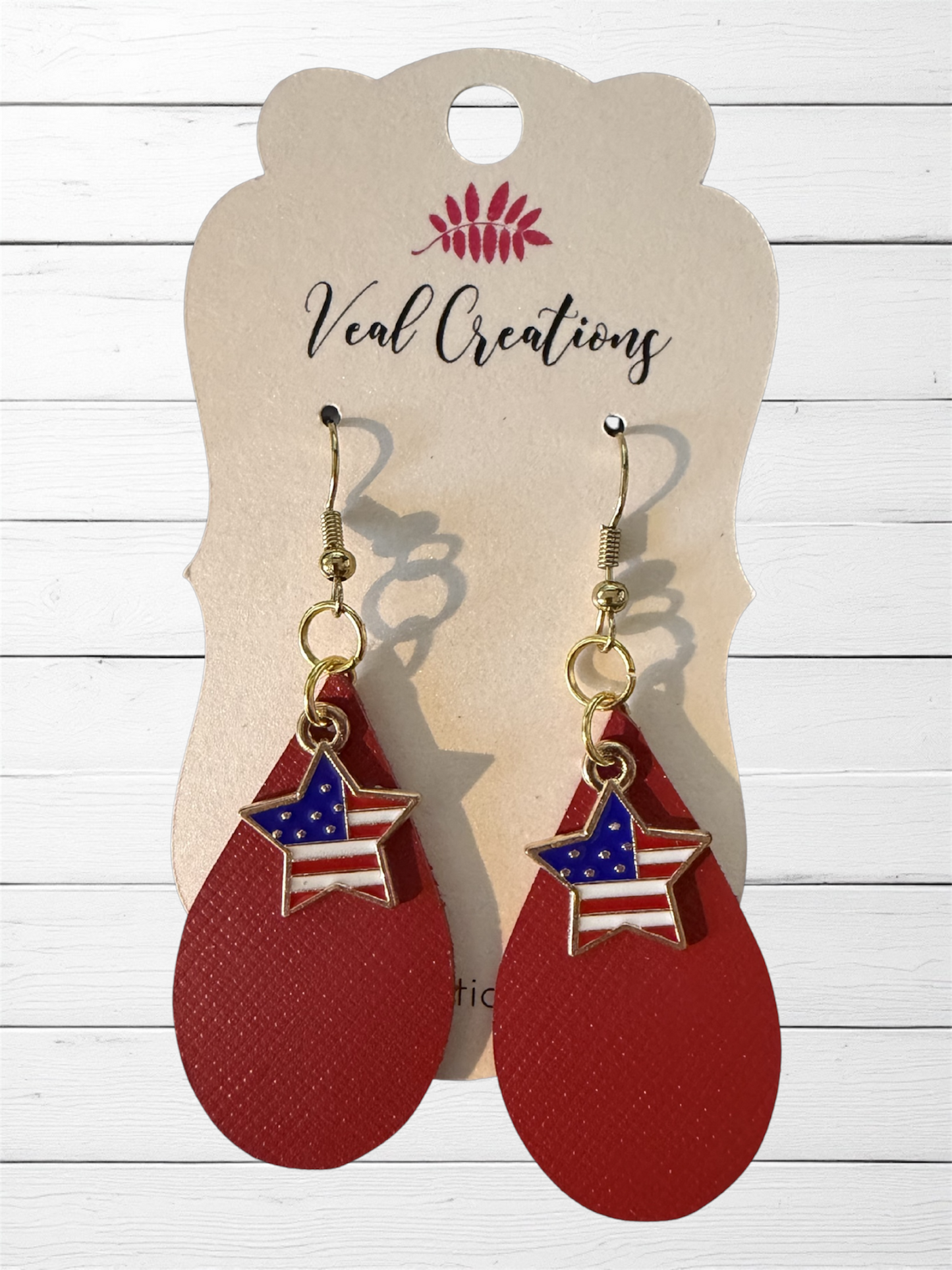 Red earrings with American flag stars on a 'Veal Creations' branded card.